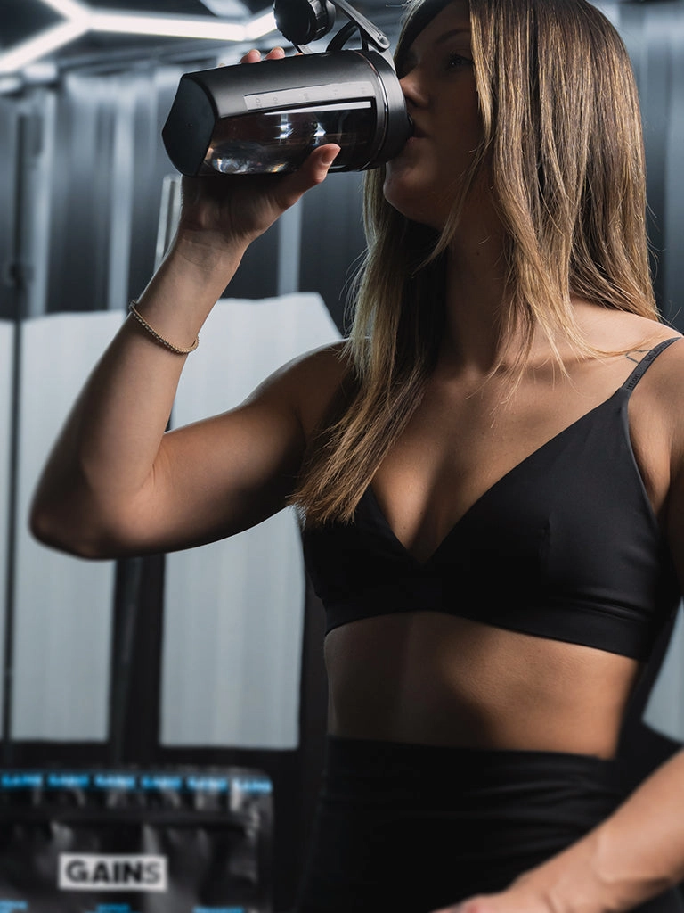 Woman drinking from a shaker bottle in a training studio
